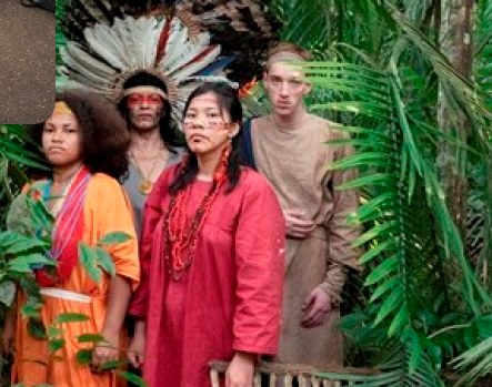 Gruppe in traditioneller Kleidung vor Palmen im Regenwald